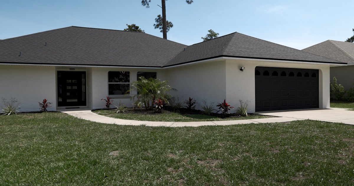The same house after the remodel, with a new dark shingle roof and white exterior