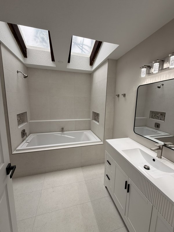 The same bathroom after the remodel, with new wall and floor tile, a new tub and vanity